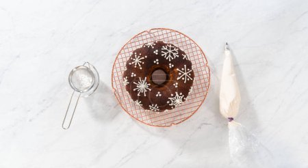 Photo for Flat lay. Decorating gingerbread bundt cake with caramel filling, buttercream frosting, and powdered sugar dusting. - Royalty Free Image