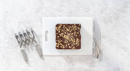 Téléchargez les photos : Pose plate. Marquage du caramel aux noisettes au chocolat à l'aide d'un coupe-pâte à roulettes pour couper en petits morceaux carrés. - en image libre de droit