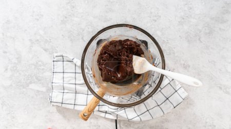 Téléchargez les photos : Pose plate. Fondre les pépites de chocolat blanc et d'autres ingrédients dans un bol de mélange en verre sur de l'eau bouillante pour préparer le caramel à la canne à sucre. - en image libre de droit