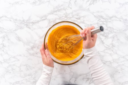 Photo for Flat lay. Mixing ingredients in a large glass mixing bowl to bake chocolate pumpkin bundt cake with toffee glaze. - Royalty Free Image