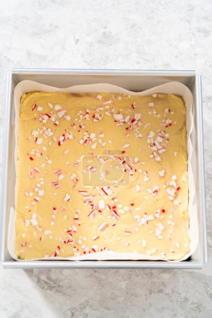 Téléchargez les photos : Enlever le caramel à la canne à sucre d'une poêle à gâteau au fromage carrée doublée de parchemin. - en image libre de droit