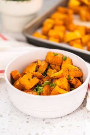 Photo for Serving oven-roasted sweet potatoes in a white ceramic bowl. - Royalty Free Image