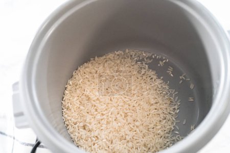 Téléchargez les photos : Riz à la coriandre. Cuisson du riz blanc à grains longs dans une cuisinière à riz. - en image libre de droit