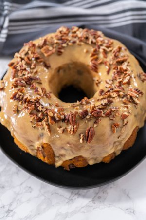 Photo for Freshly baked chocolate pumpkin bundt cake with toffee glaze topped with toasted pecans. - Royalty Free Image