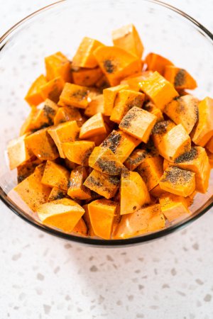 Photo for Seasoning cubed sweet potatoes to make oven-roasted sweet potatoes. - Royalty Free Image