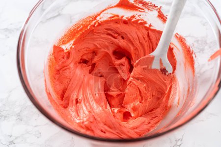 Foto de Mixing food coloring into the buttercream frosting to decorate American flag mini cupcakes. - Imagen libre de derechos