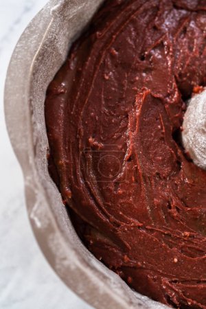 Téléchargez les photos : Remplir la casserole à gâteau en métal avec du beurre à gâteau pour cuire le gâteau bundt en velours rouge avec glaçage au fromage à la crème - en image libre de droit