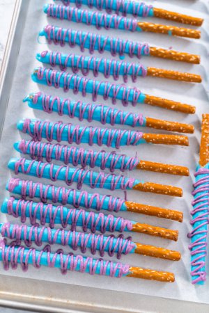 Photo for Drizzled with chocolate pretzel rods drying on a baking sheet lined with parchment paper. - Royalty Free Image