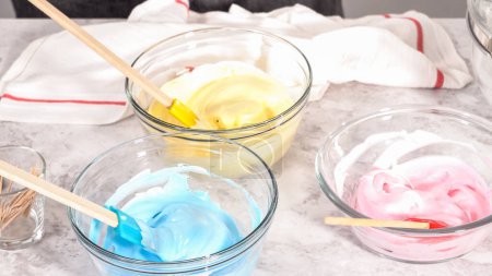 Foto de Paso a paso. Mezcla en colorante de alimentos en el merengue para hornear unicornio merengue pops cookies. - Imagen libre de derechos