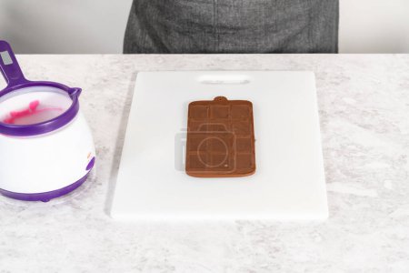 Téléchargez les photos : Enlever les mini chocolats du moule de chocolat en silicone dans une planche à découper blanche. - en image libre de droit