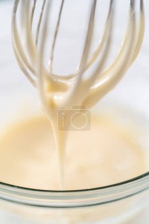 Photo for Mixing ingredients with a hand whisk to make eggnog glaze. - Royalty Free Image