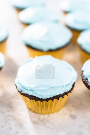 Photo for Decorating chocolate cupcakes with buttercream frosting and rainbow candy. - Royalty Free Image
