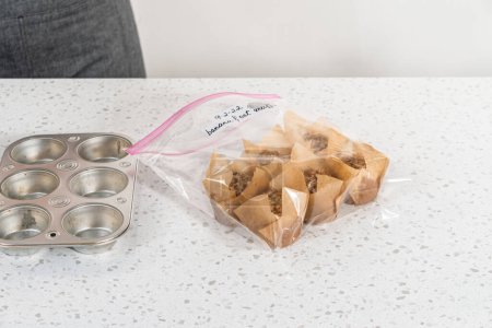 Photo for Meal prepping. Packaging banana oatmeal muffins into the plastic back to store in a freezer. - Royalty Free Image