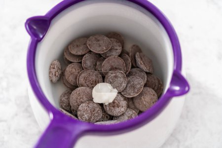 Foto de El chocolate derretido se derrite en un crisol de dulces para preparar mini chocolates gourmet con chispas. - Imagen libre de derechos