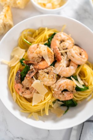 Photo for Serving garlic shrimp pasta with spinach in white ceramic bowls. - Royalty Free Image
