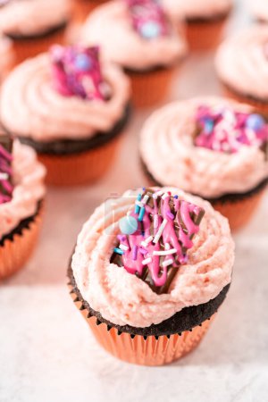 Téléchargez les photos : Cupcakes fraises au chocolat fraîchement cuits garnis de mini chocolats roses gourmands. - en image libre de droit
