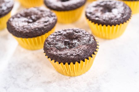 Téléchargez les photos : Refroidissement cupcakes au chocolat fraîchement cuits à décorer avec glaçage à la crème au beurre. - en image libre de droit