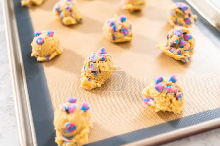 Téléchargez les photos : Cuillères de pâte à biscuits réfrigérées sur la plaque à pâtisserie pour cuire des biscuits aux pépites de chocolat à la licorne. - en image libre de droit