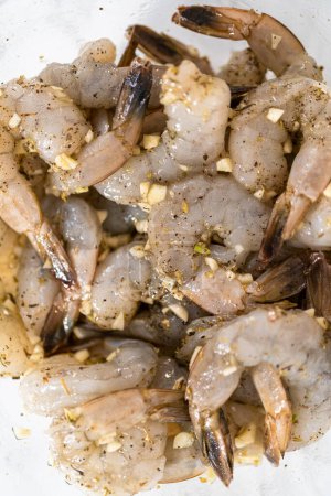 Téléchargez les photos : Faire mariner les crevettes crues avec de l'ail et des épices pour préparer des pâtes aux crevettes avec des épinards.. - en image libre de droit