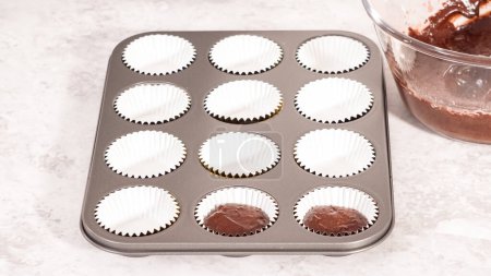Téléchargez les photos : Pas à pas. Ramasser la pâte de cupcake au chocolat dans les doublures de cupcake. - en image libre de droit