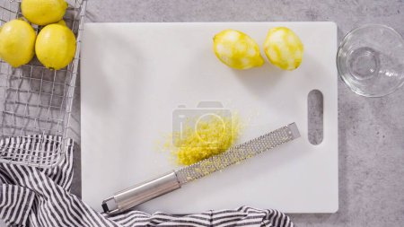 Téléchargez les photos : Pose plate. Zesting citrons biologiques pour faire cuire un gâteau de livre de citron. - en image libre de droit