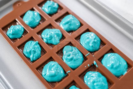 Foto de Rellenar moldes de silicona de chocolate con chocolate derretido para preparar mini barras de chocolate de sirena. - Imagen libre de derechos