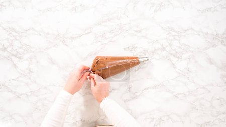 Téléchargez les photos : Pose plate. Pas à pas. glaçage ganache chocolat dans un sac de tuyauterie avec une pointe en métal. - en image libre de droit