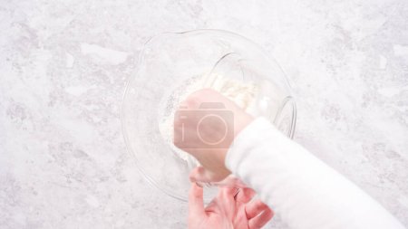Téléchargez les photos : Pose plate. Pas à pas. Mélanger les ingrédients dans un bol à mélanger en verre pour préparer le gâteau bundt en velours rouge. - en image libre de droit