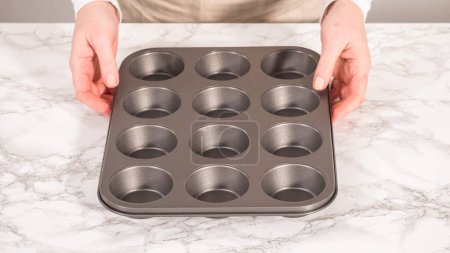 Photo for Step by step. Baking chocolate cupcakes. Lining metal cupcake pan with foil cupcake liners. - Royalty Free Image
