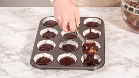 Foto de Step by step. Baking chocolate cupcakes. Scooping chocolate cupcake batter into a cupcake pan. - Imagen libre de derechos