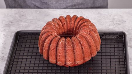 Téléchargez les photos : Pas à pas. Refroidissement gâteau bundt en velours rouge fraîchement cuit sur un séchoir de cuisine. - en image libre de droit