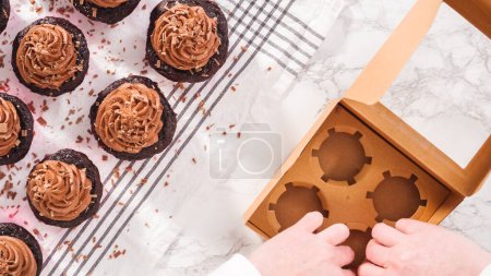 Photo for Flat lay. Step by step. Packaging chocolate cupcakes with chocolate ganache frosting into a paper cupcake box. - Royalty Free Image