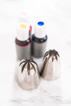 Photo for Food coloring and metal piping tips for baking on a marble surface. - Royalty Free Image