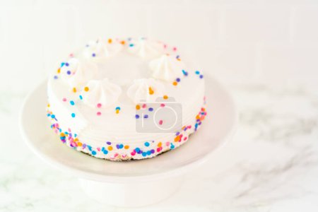 Foto de Pequeño pastel de cumpleaños blanco con funfetti espolvorea en un plato de pastel blanco. - Imagen libre de derechos