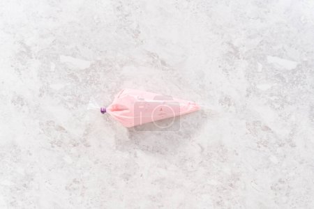 Photo for Flat lay. Pink vanilla buttercream frosting in a piping bag. - Royalty Free Image