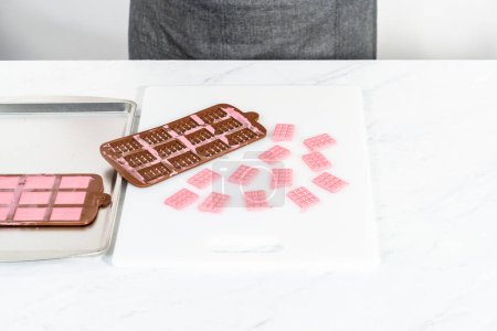 Photo for Removing mini pink chocolates from silicone chocolate mold. - Royalty Free Image