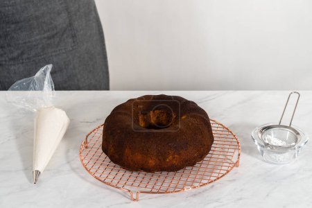 Téléchargez les photos : Décorer le gâteau bundt en pain d'épice avec garniture au caramel, glaçage à la crème au beurre et saupoudrage au sucre en poudre. - en image libre de droit