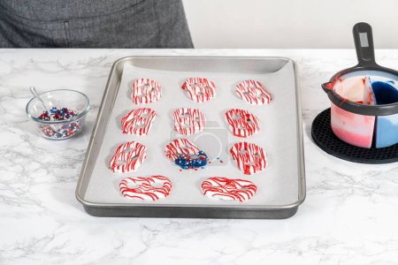 Photo for Flat lay. Dipping pretzels twists into melted chocolate to make red, white, and blue chocolate-covered pretzel twists. - Royalty Free Image