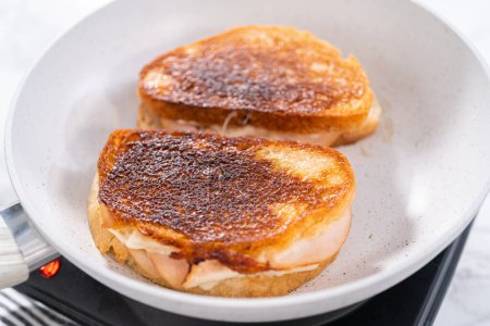 Téléchargez les photos : Prepare provolone and apple grilled cheese sandwich on a nonstick frying pan. - en image libre de droit