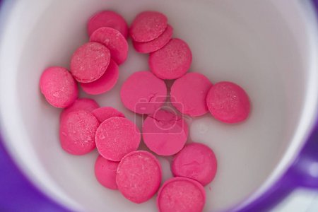 Photo for Melting pink chocolate melts to make mini pink chocolates. - Royalty Free Image