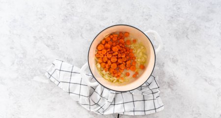 Foto de Acostado. Salteando verduras en horno holandés esmaltado de hierro fundido para cocinar sopa de guisantes partida. - Imagen libre de derechos