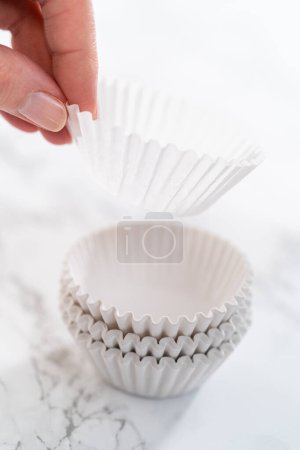 Foto de Nuevos revestimientos de cupcakes de papel blanco en el mostrador de la cocina. - Imagen libre de derechos