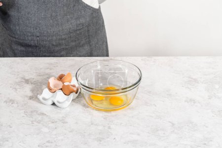 Téléchargez les photos : Mélanger les ingrédients humides dans un petit bol de mélange en verre pour faire cuire un gâteau bundt aux carottes avec glaçage au fromage à la crème. - en image libre de droit