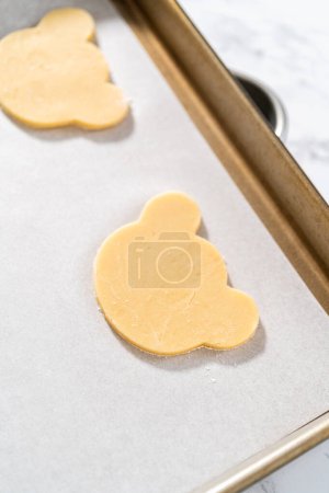 Photo for Rolling cookie dough and cutting out panda-shaped shortbread cookies. - Royalty Free Image