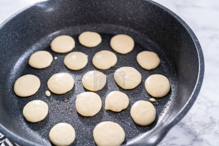 Frying mini pancake cereal in a nonstick frying pan.