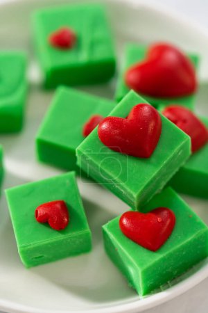 Téléchargez les photos : Fudge vert chocolat fait maison avec des morceaux carrés de cœurs rouges sur une assiette blanche. - en image libre de droit