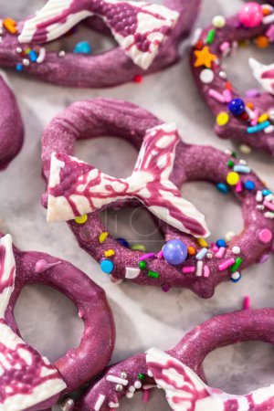 Photo for Homemade chocolate-dipped pretzel twists decorated with colorful sprinkles and chocolate mermaid tails on a white plate. - Royalty Free Image