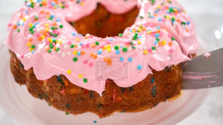 Photo for Step by step. Slicing funfettti bundt cake with pink buttercream frosting on top and buttercream filling inside. - Royalty Free Image