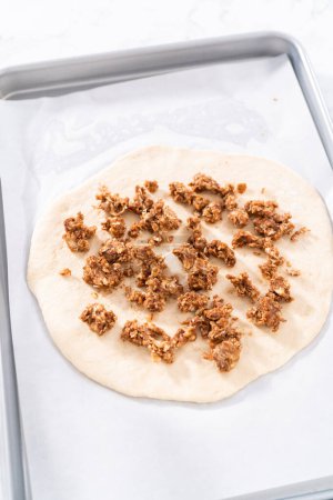 Téléchargez les photos : Préparation de pizza dessert à la cannelle sur une plaque à pâtisserie tapissée de papier parchemin. - en image libre de droit