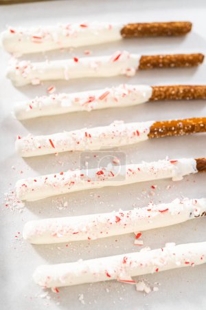 Téléchargez les photos : Les tiges de bretzel recouvertes de chocolat de canne à sucre maison séchent sur une plaque à pâtisserie tapissée de papier parchemin. - en image libre de droit